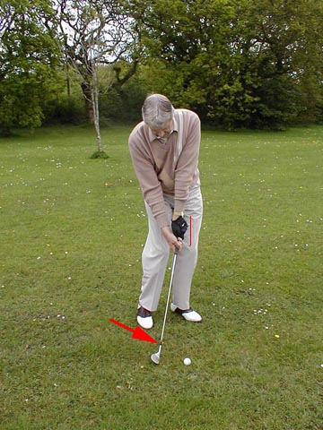 The club is being aimed at  a point where the golf ball is actually touching the grass.